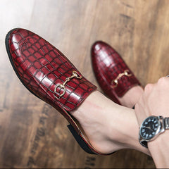 Red croc-embossed leather mules on hand, side view of bit strap and sole