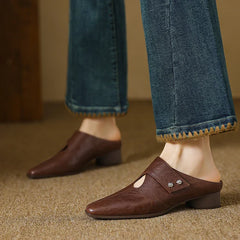 Brown leather mule on foot with side cutout and stud detail, low block heel