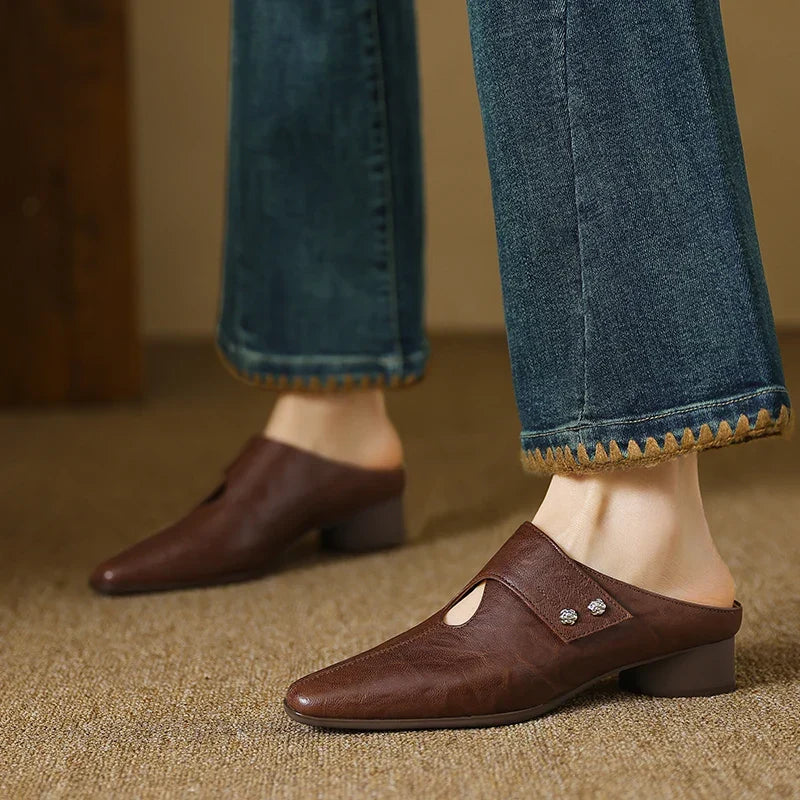 Brown leather mule on foot with side cutout and stud detail, low block heel