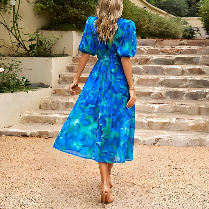 Blue V-neck midi dress with puff sleeves and ruched waist, flowing skirt silhouette.