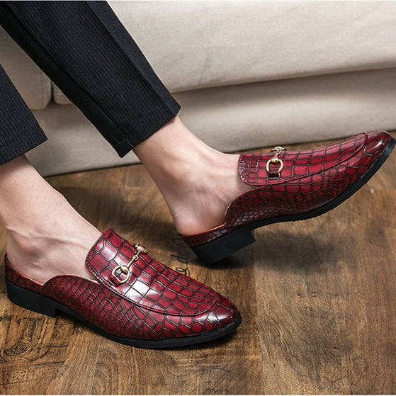 Red croc-embossed leather mules on feet with metal bit strap and block heel
