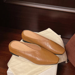 Tan pointed-toe mules with low flat heel and slip-on backless design.