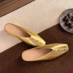 Gold metallic slip-on mules with pointed toe and low heel, shown from top