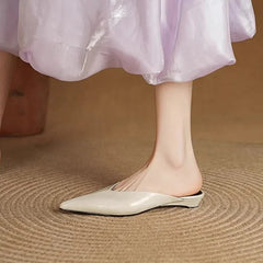 Cream leather mules with pointed toe and low heel on model’s feet