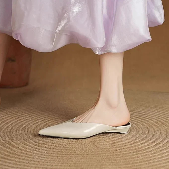 Cream leather mules with pointed toe and low heel on model’s feet