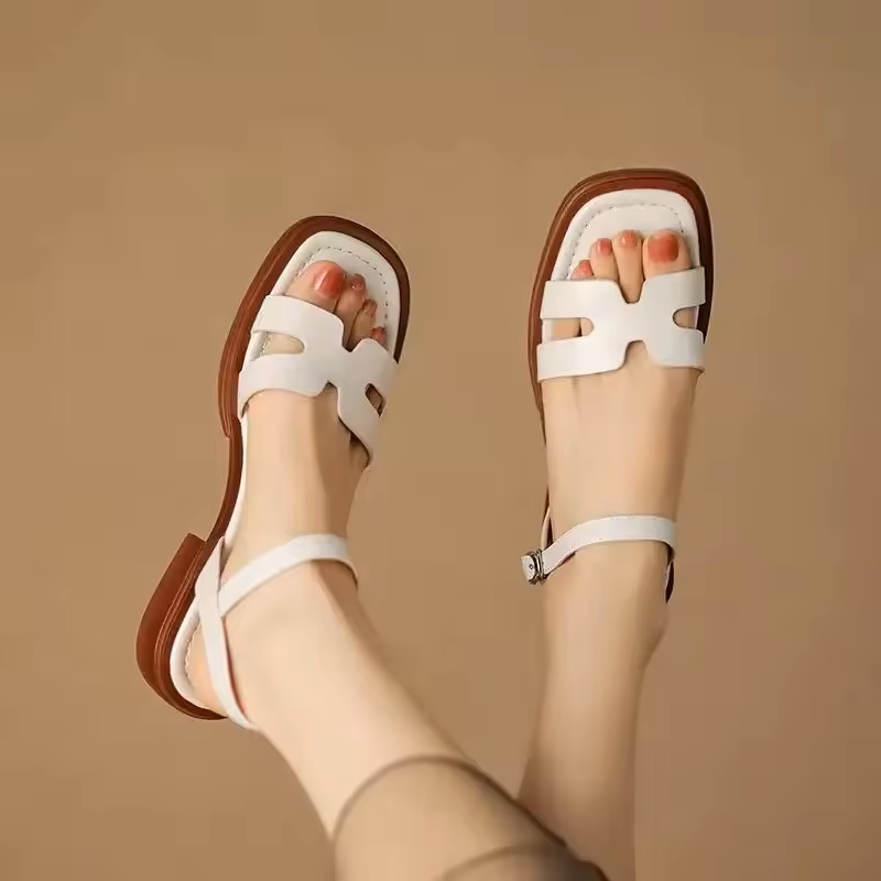 White Roman-style leather sandals with brown trim, ankle strap, and open toe