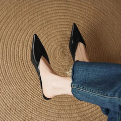 Black leather pointed-toe mules with low heel, worn with rolled jeans.