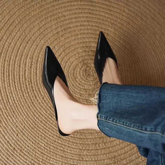 Black leather pointed-toe mules with low heel, worn with rolled jeans.