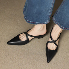 Black genuine leather mules with pointed toe and T-strap slingback on model’s feet