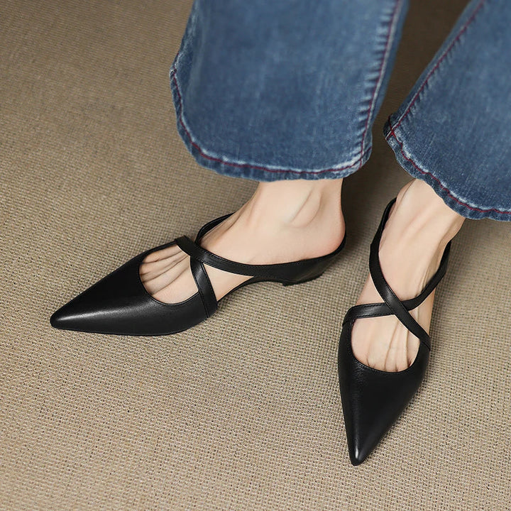 Black genuine leather mules with pointed toe and T-strap slingback on model’s feet