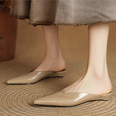 Beige leather mules on feet with pointed toe and low heel