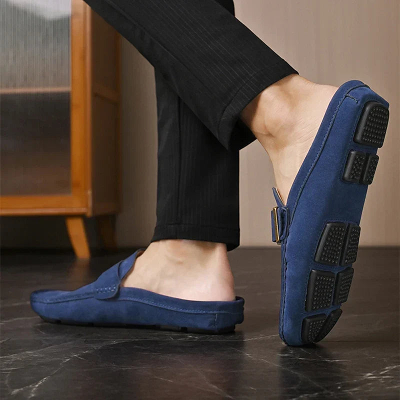 Blue suede mules showing outsole tread and square buckle strap on side