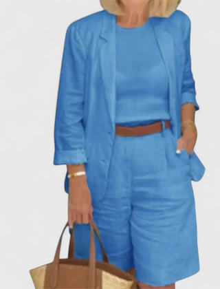 Blue 2-piece suit set with blazer jacket and shorts, styled with waist belt and tote