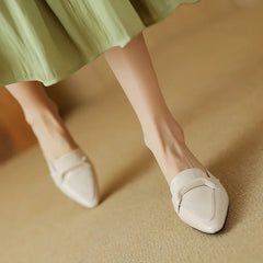 Beige leather mules on a foot, slip-on V strap and low block heel