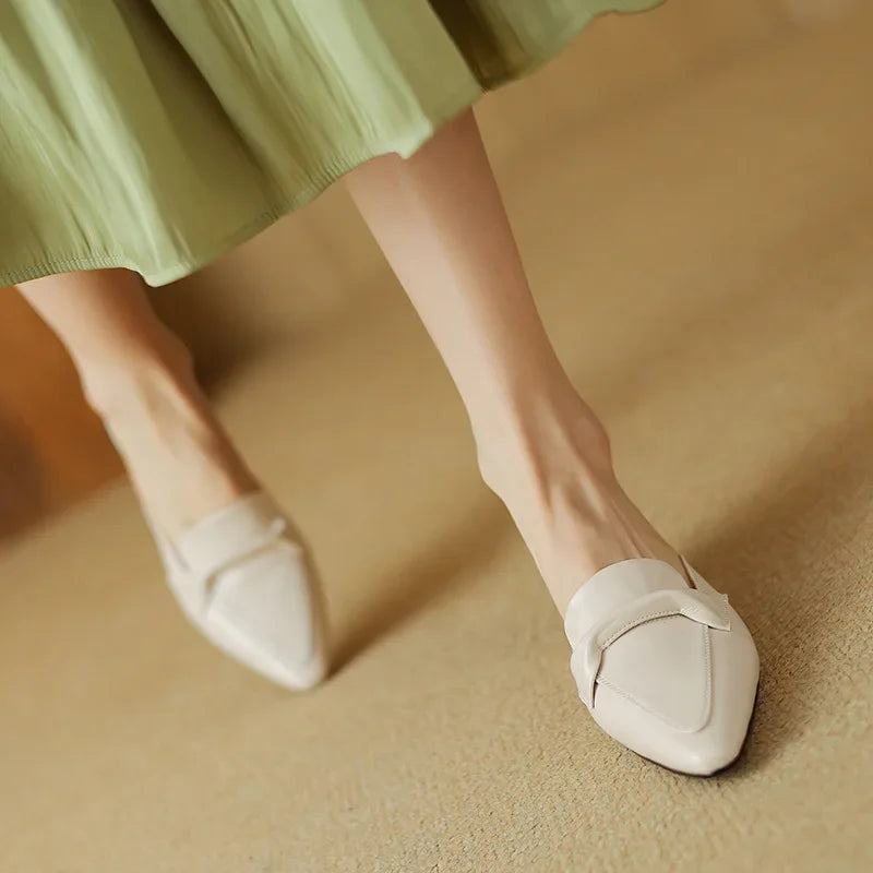 Beige leather mules on a foot, slip-on V strap and low block heel