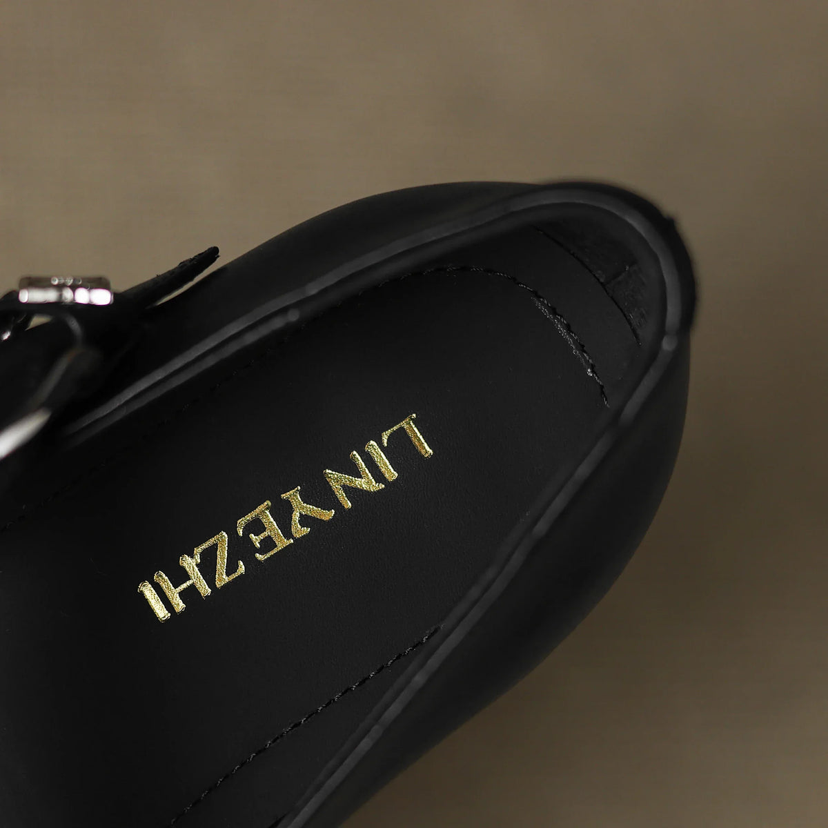 Black leather flat with gold-tone logo detail on the insole
