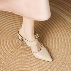 Beige leather heels featuring pointed toe and gold rosette ankle strap with block heel
