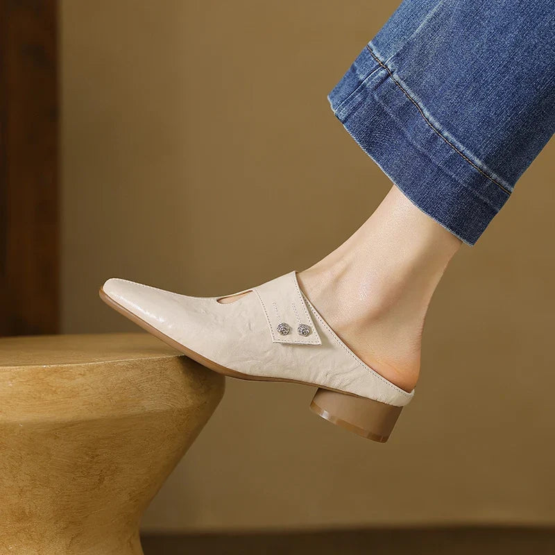 Beige leather mules with pointed toe, decorative studs, and low block heel