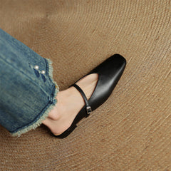 Black genuine leather mule with ankle strap and pointed toe, worn with denim