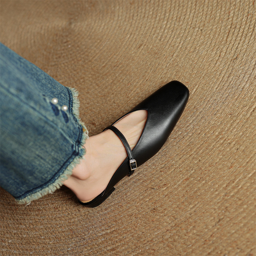 Black genuine leather mule with ankle strap and pointed toe, worn with denim