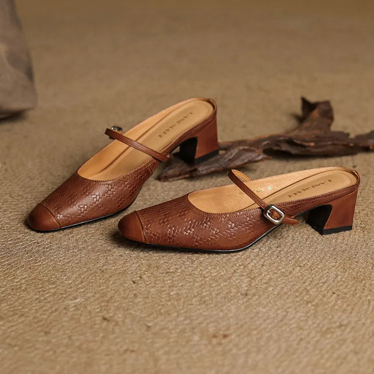 Pair of brown embossed leather mules with square toe, buckle strap, and block heel