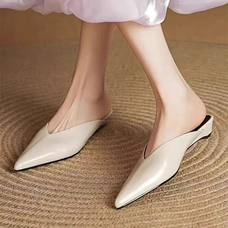 Cream leather mule shoes with pointed toe and low heel on feet