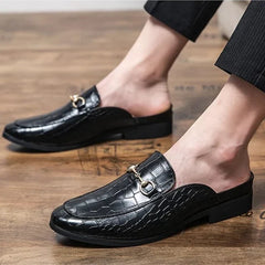 Black croc-embossed leather mules on feet, slip-on with metal bit strap