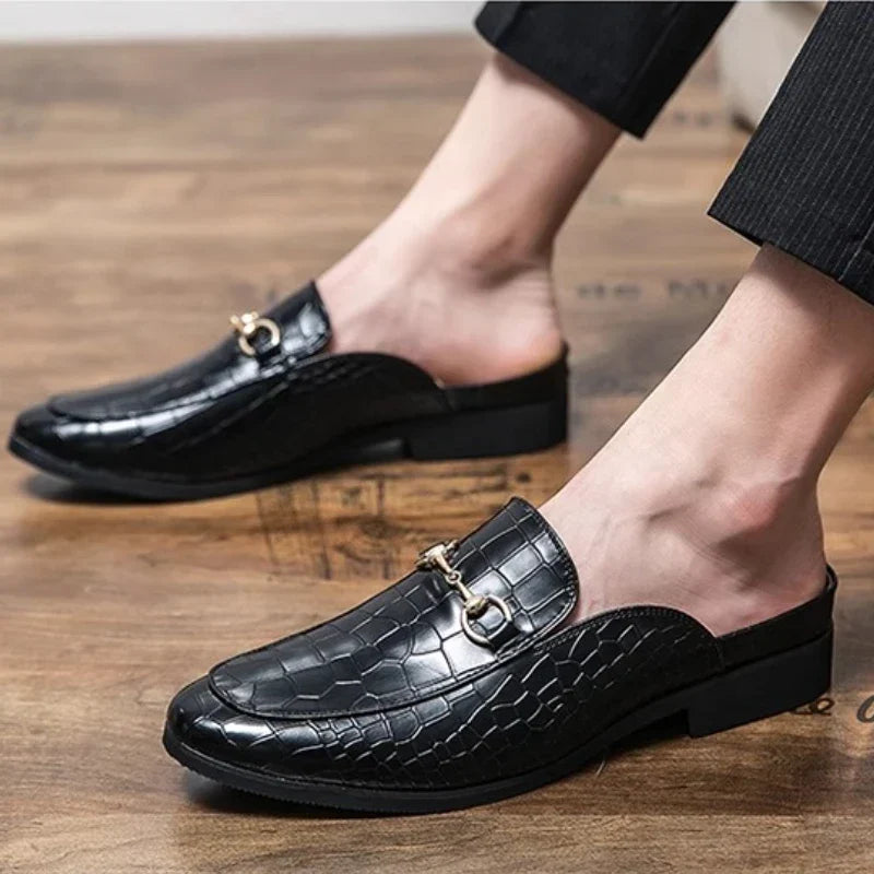Black croc-embossed leather mules on feet, slip-on with metal bit strap