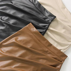 Flat lay of leather midi skirts in black, cream, and tan with smooth finish