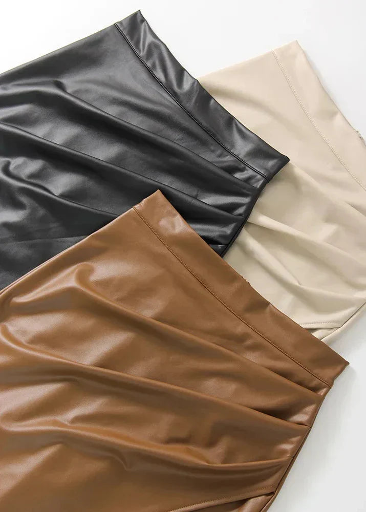 Flat lay of leather midi skirts in black, cream, and tan with smooth finish