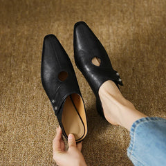 Black leather mules pair with side cutouts and small stud detail, low heel