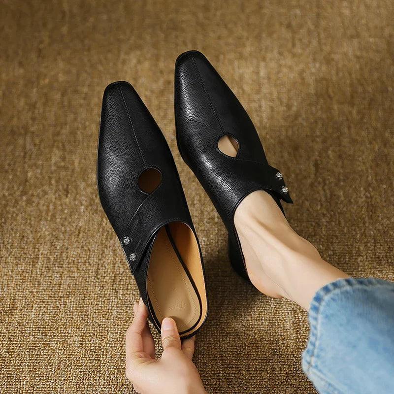Black leather mules pair with side cutouts and small stud detail, low heel