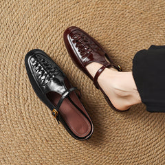 Black and brown leather mules with braided vamp, sling strap, and gold buckle