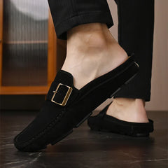 Black suede mules with square metal buckle strap and stitched moc toe, slip-on