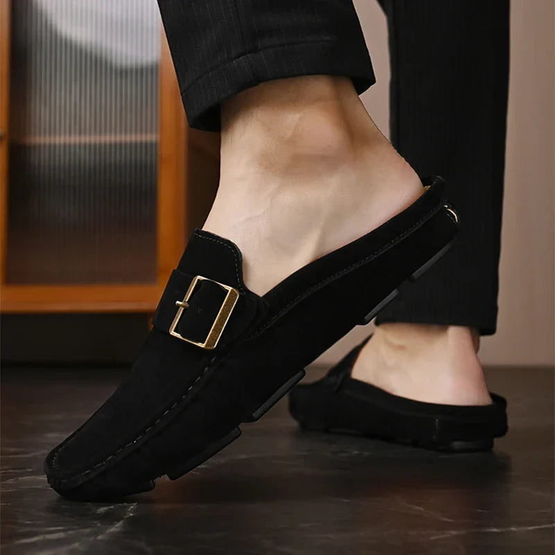 Black suede mules with square metal buckle strap and stitched moc toe, slip-on