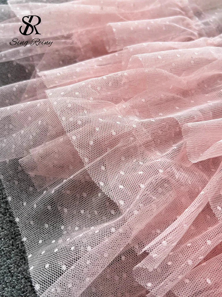 Sheer pink tulle fabric with small dotted texture and layered ruffle detail