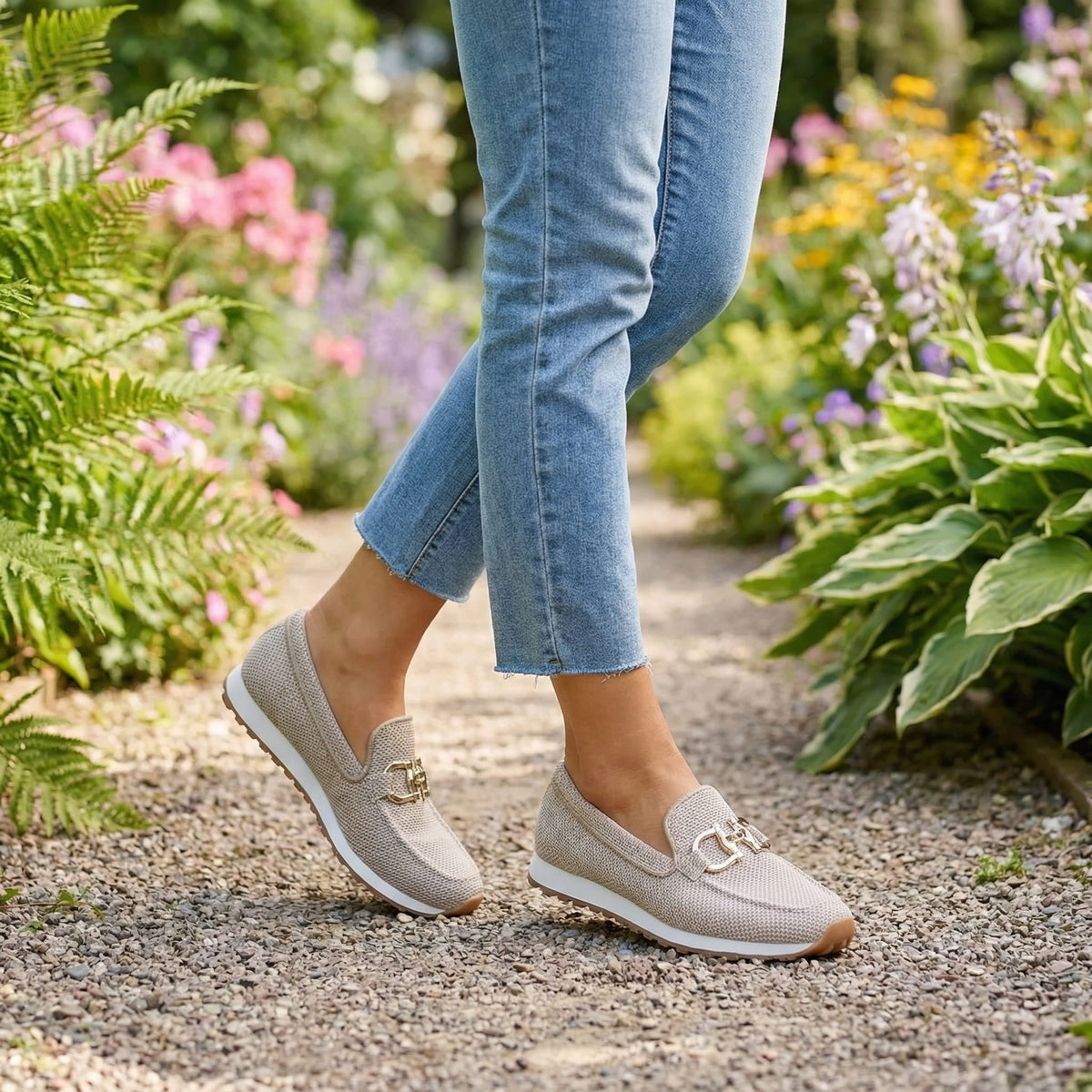 Beige loafer sneakers on feet with gold buckle ornament and textured knit fabric