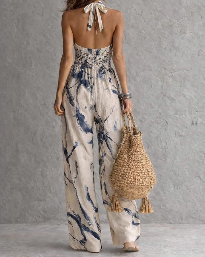 Ink-wash halter jumpsuit with open back neck-tie and wide-leg pant silhouette.