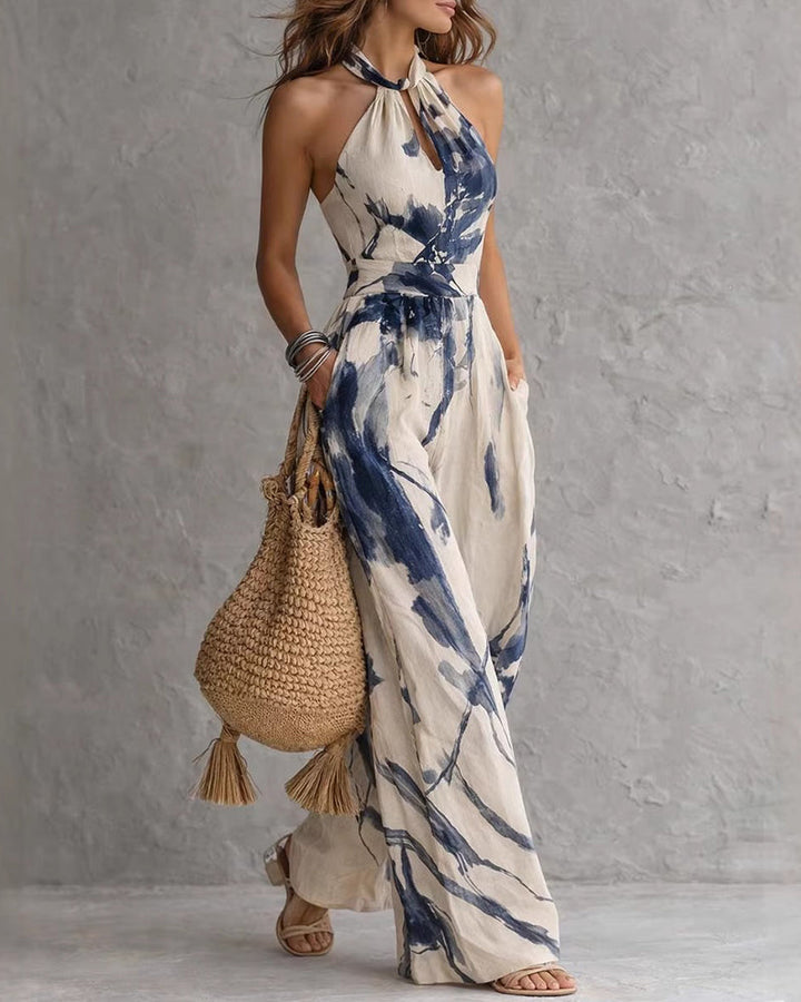 Blue ink-wash halter jumpsuit with neck tie, sleeveless bodice, and flowing wide legs.