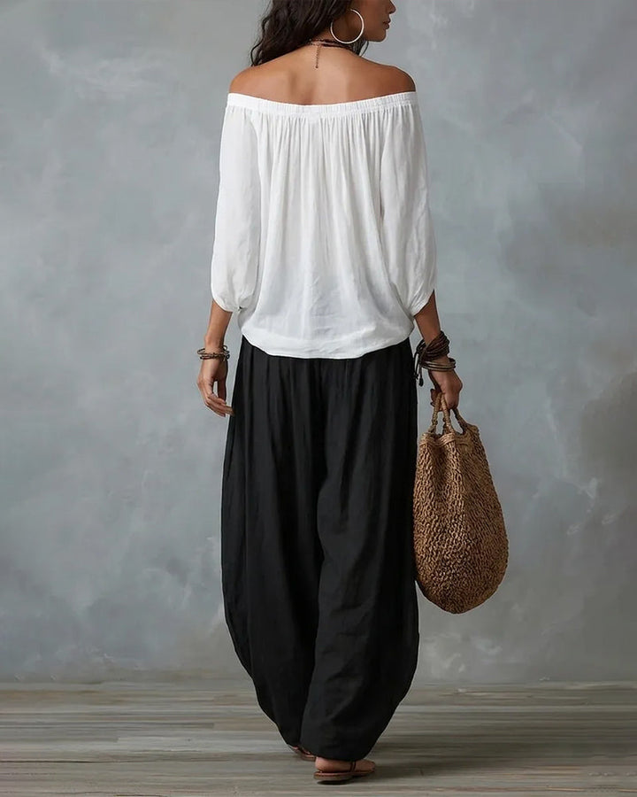 White off-shoulder top and black draped harem pants resort set, back view