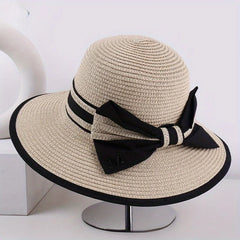 Beige wide brim sun hat with black band, striped tie, and bow