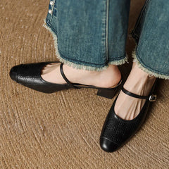 Black embossed leather mule with square toe and ankle strap, worn with rolled denim