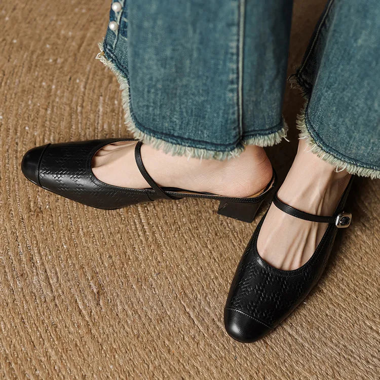 Black embossed leather mule with square toe and ankle strap, worn with rolled denim