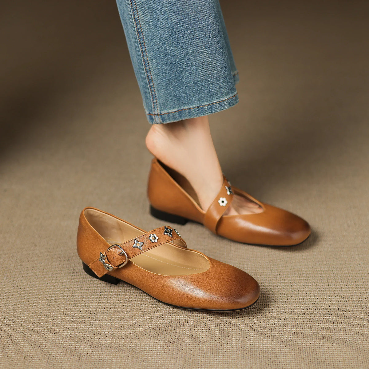 Tan leather flats, low-profile buckle strap with star-flower ornament detail