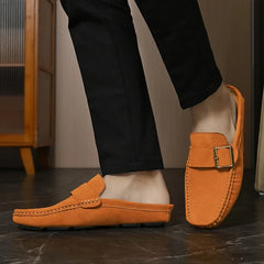Tan suede loafer-style mules with buckle strap on feet