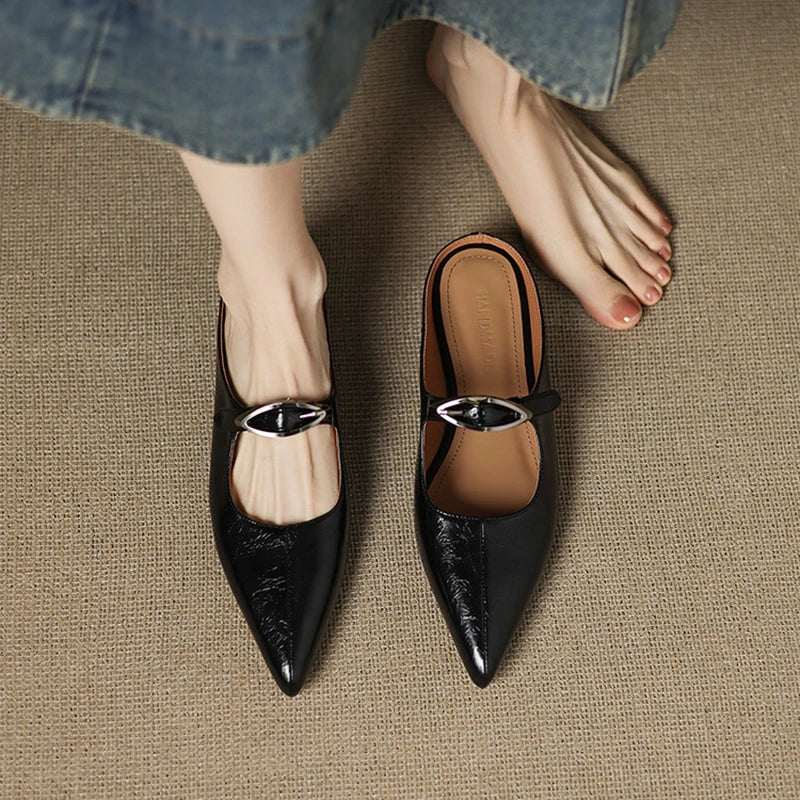 Pair of black leather mules with pointed toe and shiny buckle slingback strap