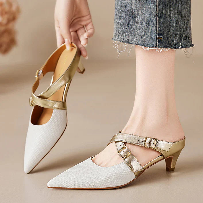 White textured leather mule with pointed toe, gold buckled straps, and low block heel.