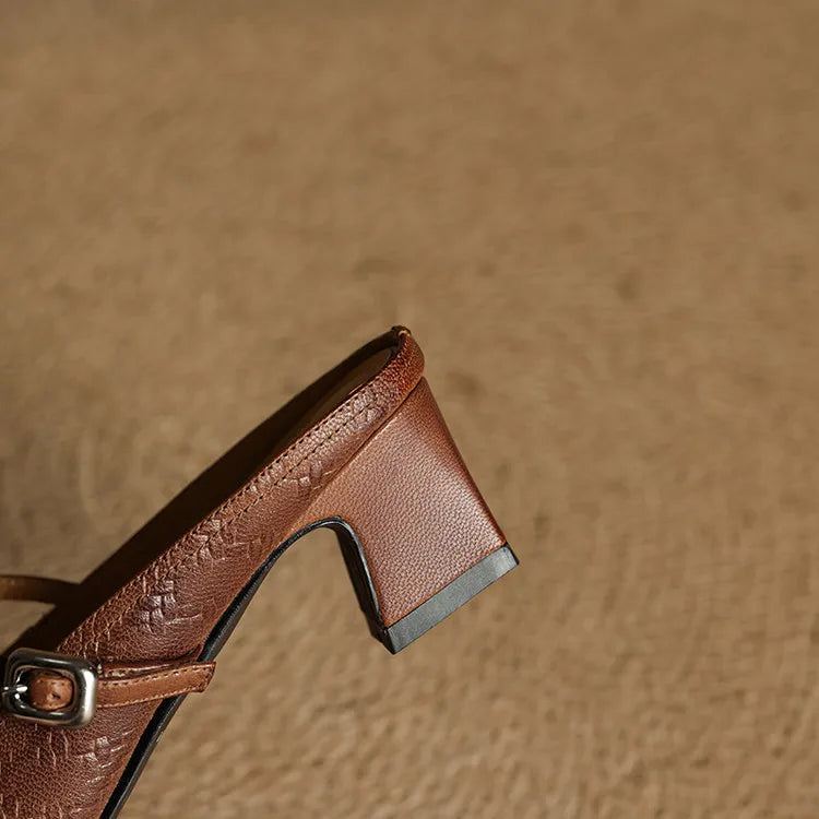Brown mule detail: square heel, side panel, and embossed leather strap with buckle