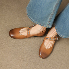 Tan leather flats with T-strap buckle and star-flower studs on upper