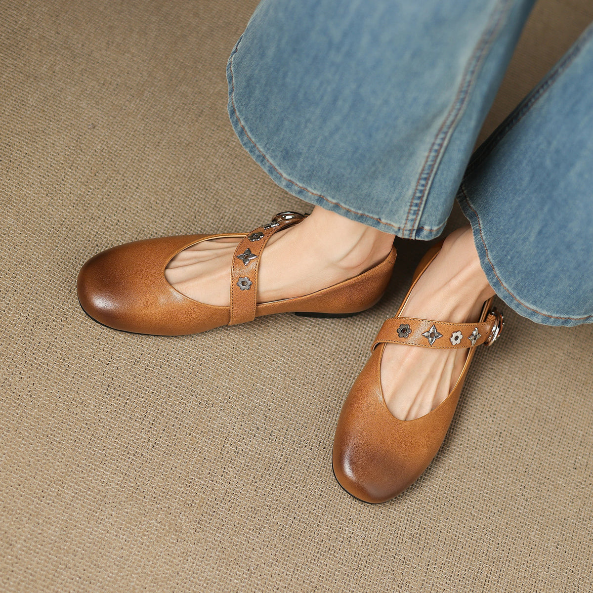 Tan leather flats with T-strap buckle and star-flower studs on upper